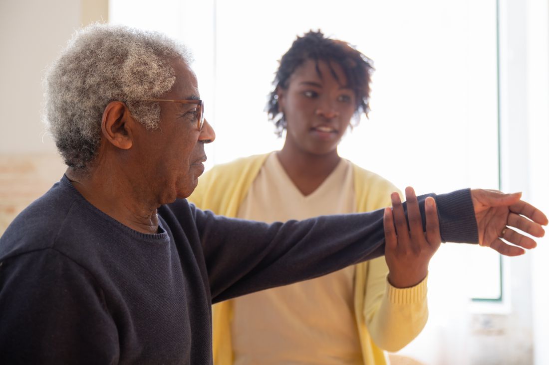 A woman assisting an older man with gentle arm movements