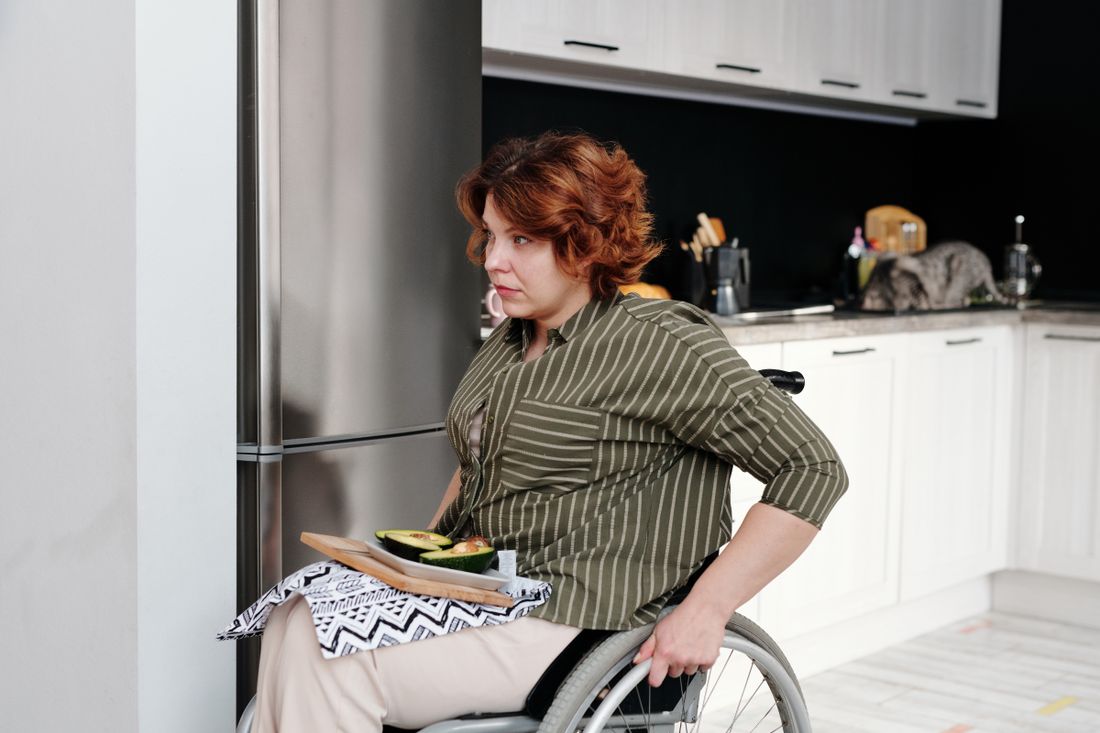 A wheelchair user with prepared food in a kitchen